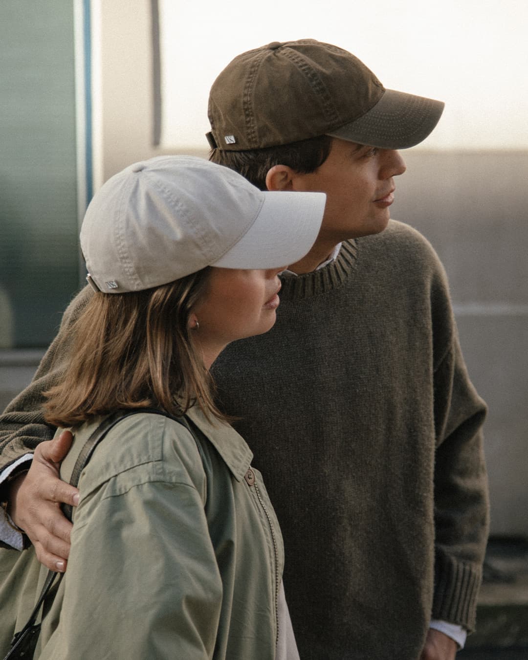 Side view of female and male model wearing light beige and beige washed cotton caps in the streets of oslo