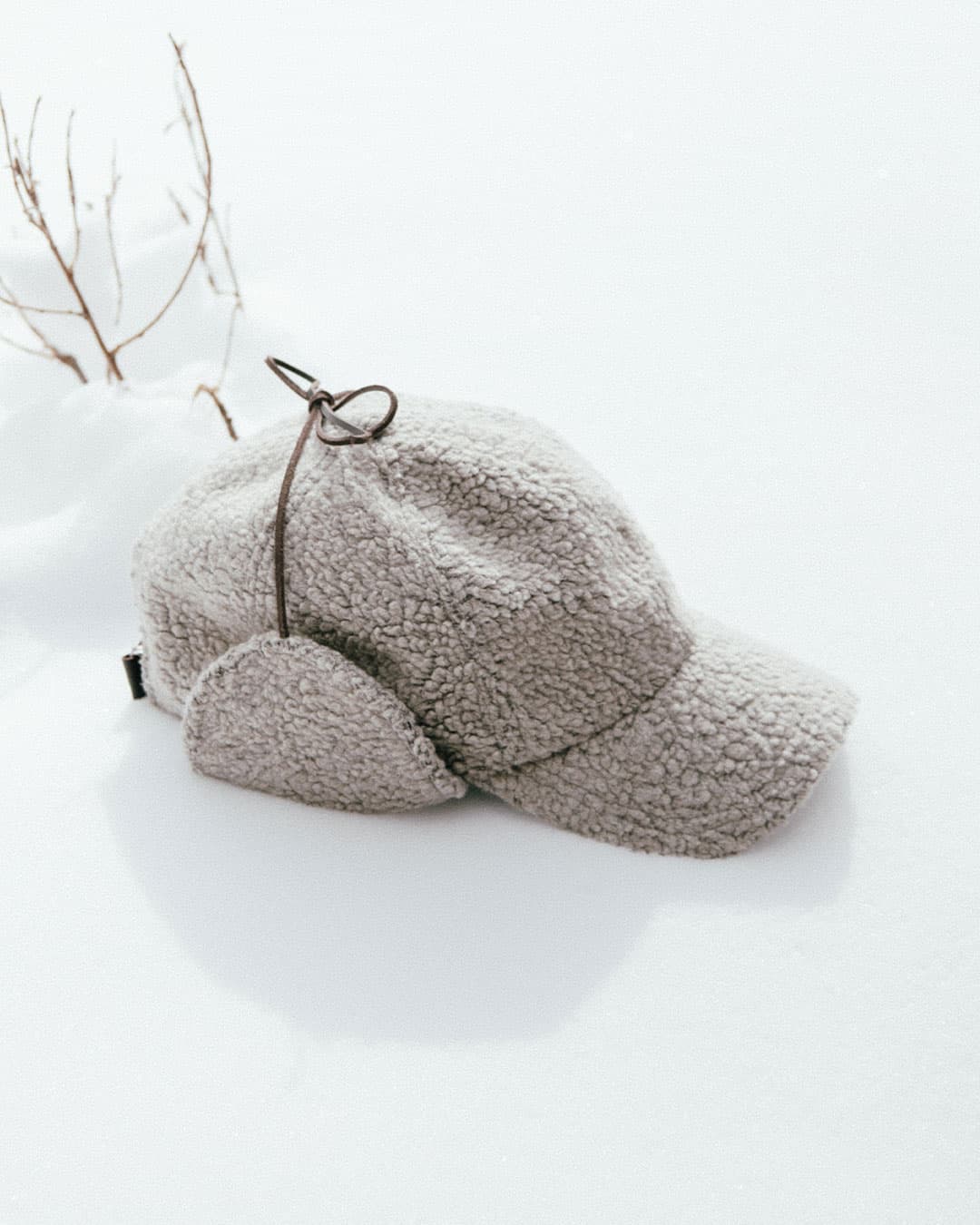 Side view of a legacy soft teddy taupe cap from Varsity Headwear on snow