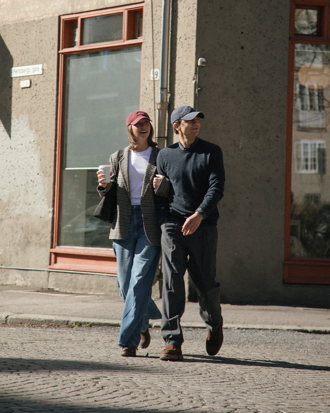 Male and female wearing burgundy and navy washed cotton cap in the streets of Oslo