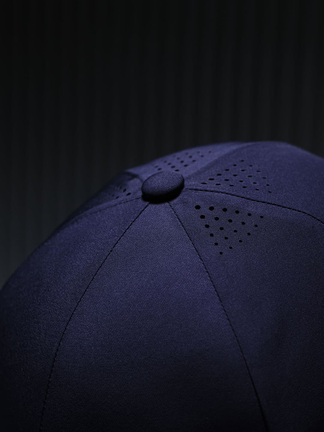 Detailed view of ventilation holes on a navy mid intensity sport cap from Varsity Headwear