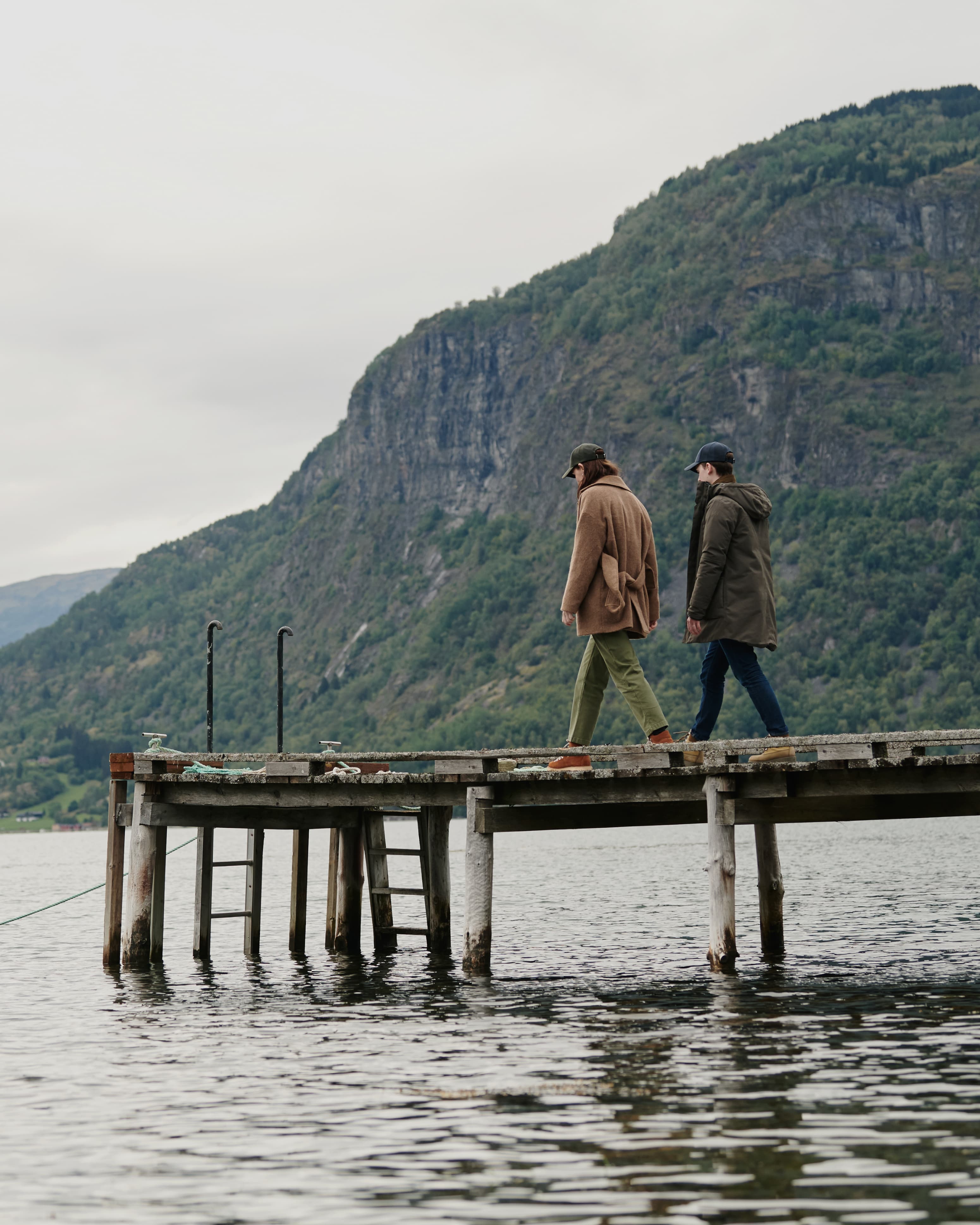 Lifestyle image of female and male model in Norwegian landscape wearing varsity headwear baseball caps