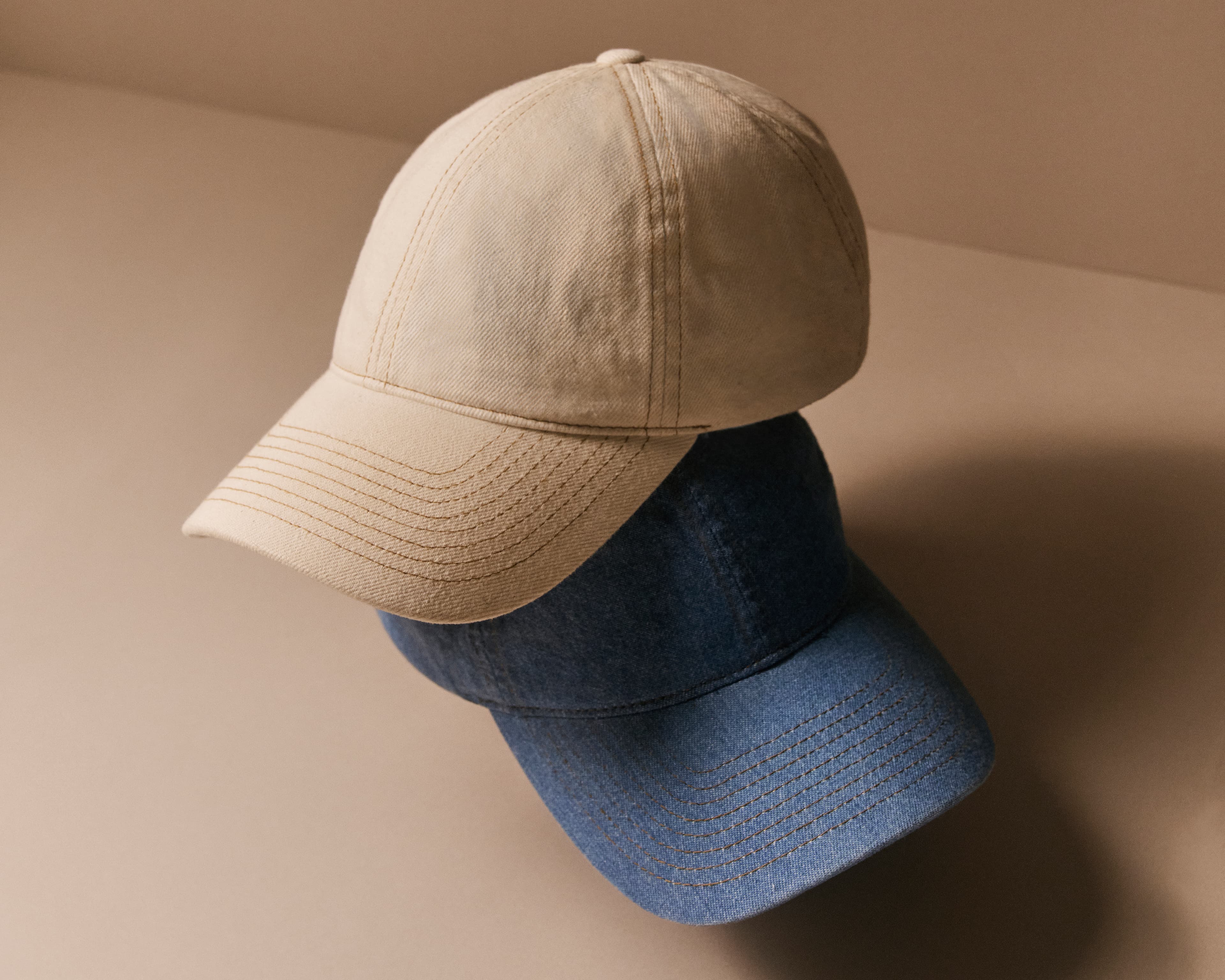 Front view of a white and a blue denim cap from varsity headwear in the legacy soft shape
